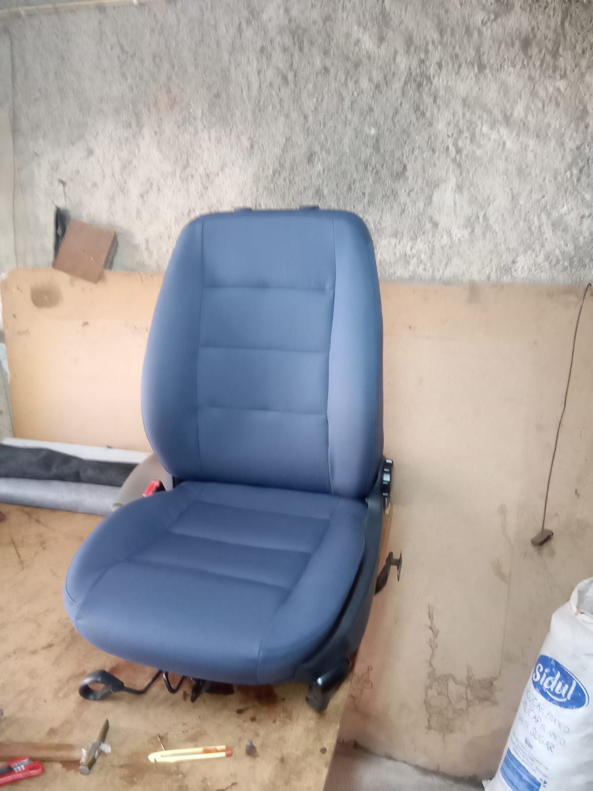 Banco de automóvel totalmente reestofado em tecido azul, na oficina