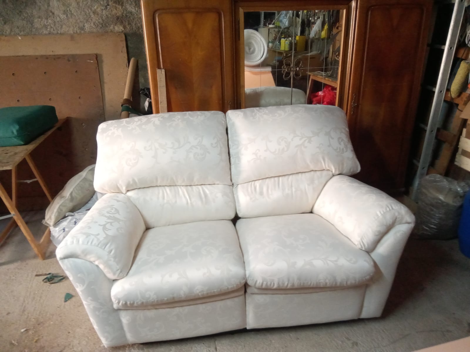 Sofá de dois lugares estofado em tecido branco com padrão floral em relevo, acabado na oficina