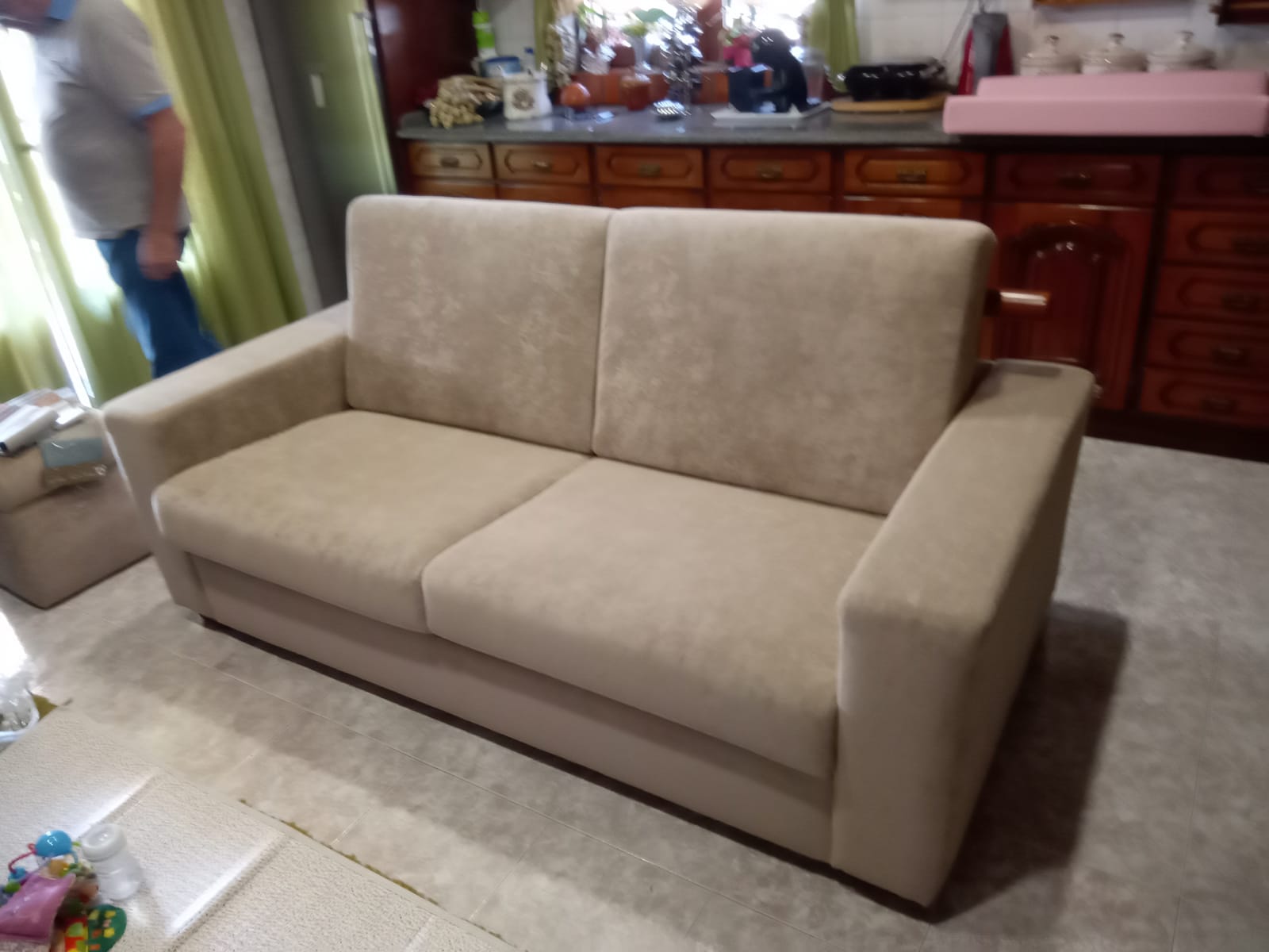 Sofá de três lugares renovado com tecido bege e almofadas de enchimento novo, já entregue em casa do cliente